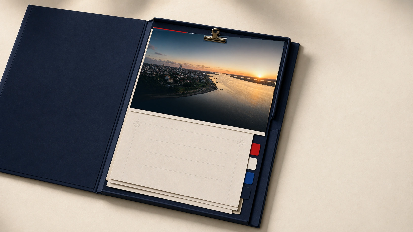 An open navy dossier folder holding a clipped photograph of the Asuncion riverfront at sunset